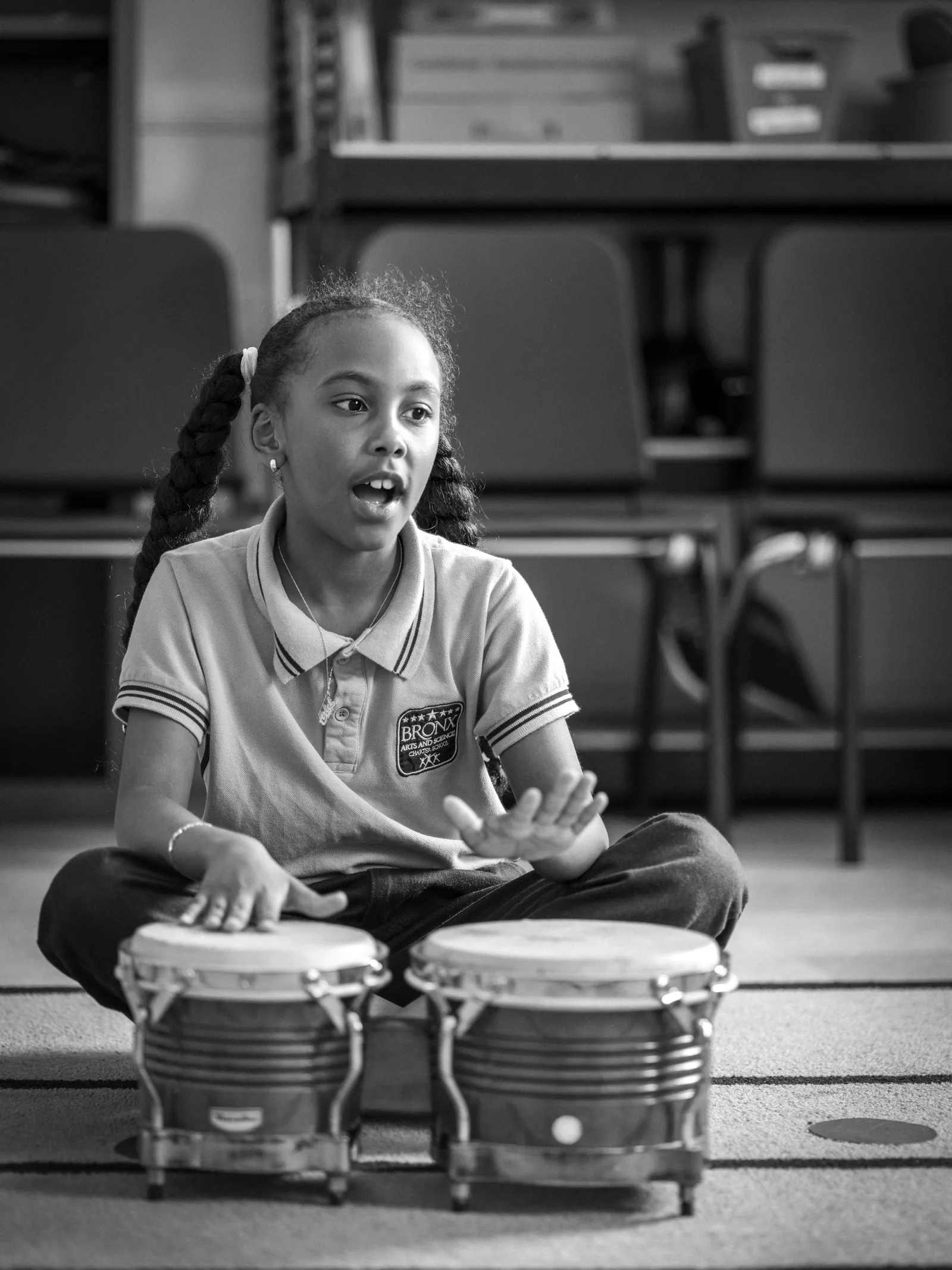 An elementary student playing bongo drums in music class