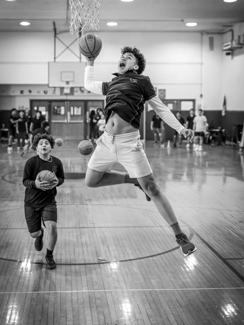 A student dunking a basketball in the school gym