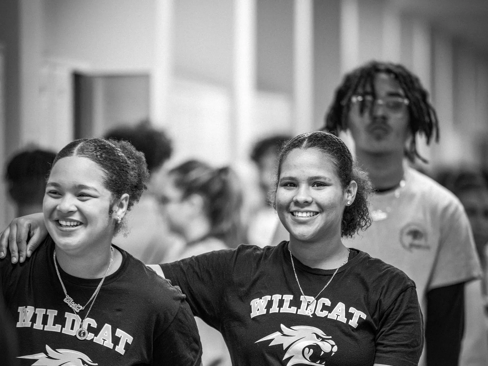 Two students in athletics shirts walking through the gym