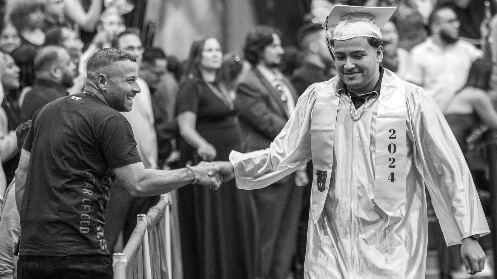 A graduate greeting families along the commencement aisle