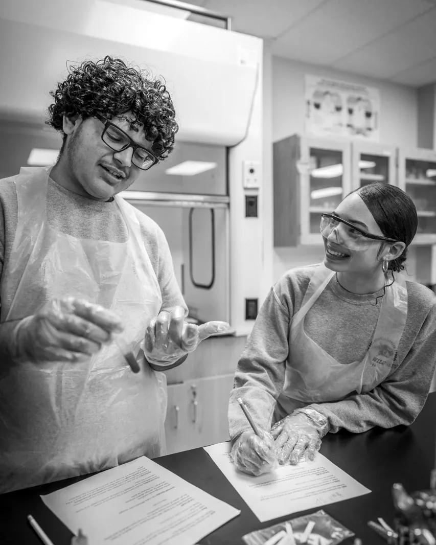 Students in lab coats working together at a science bench.